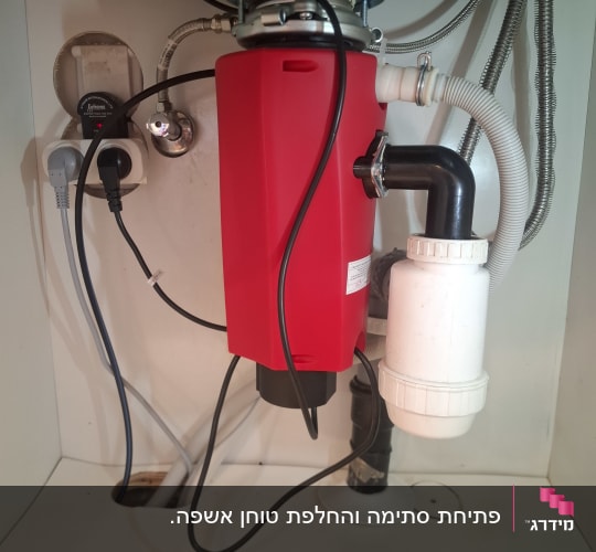 מתקן אדום מתחת לכיור עם צינורות וחיבורים